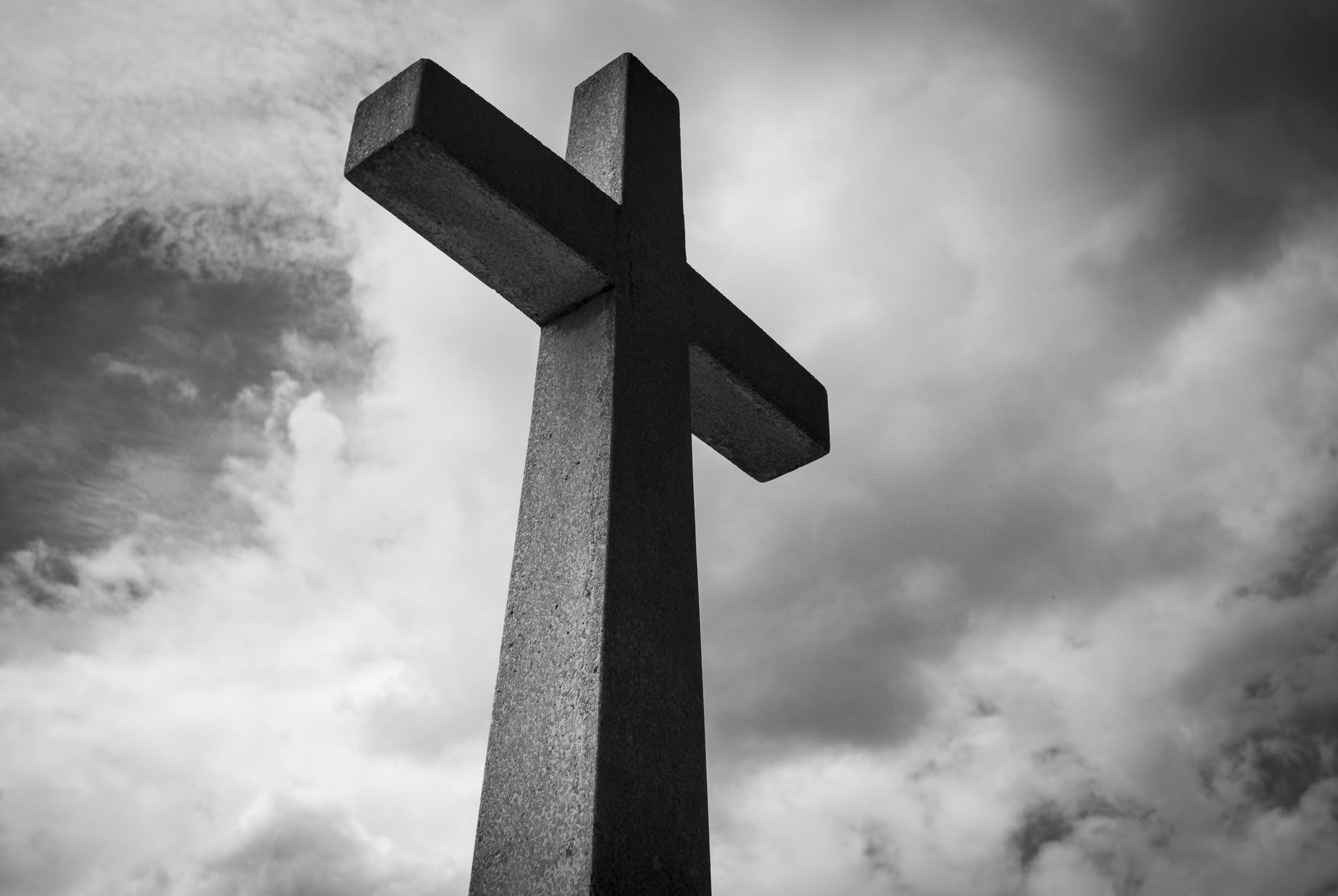 A black and white cross against clouds. Jesus is an unusual king.