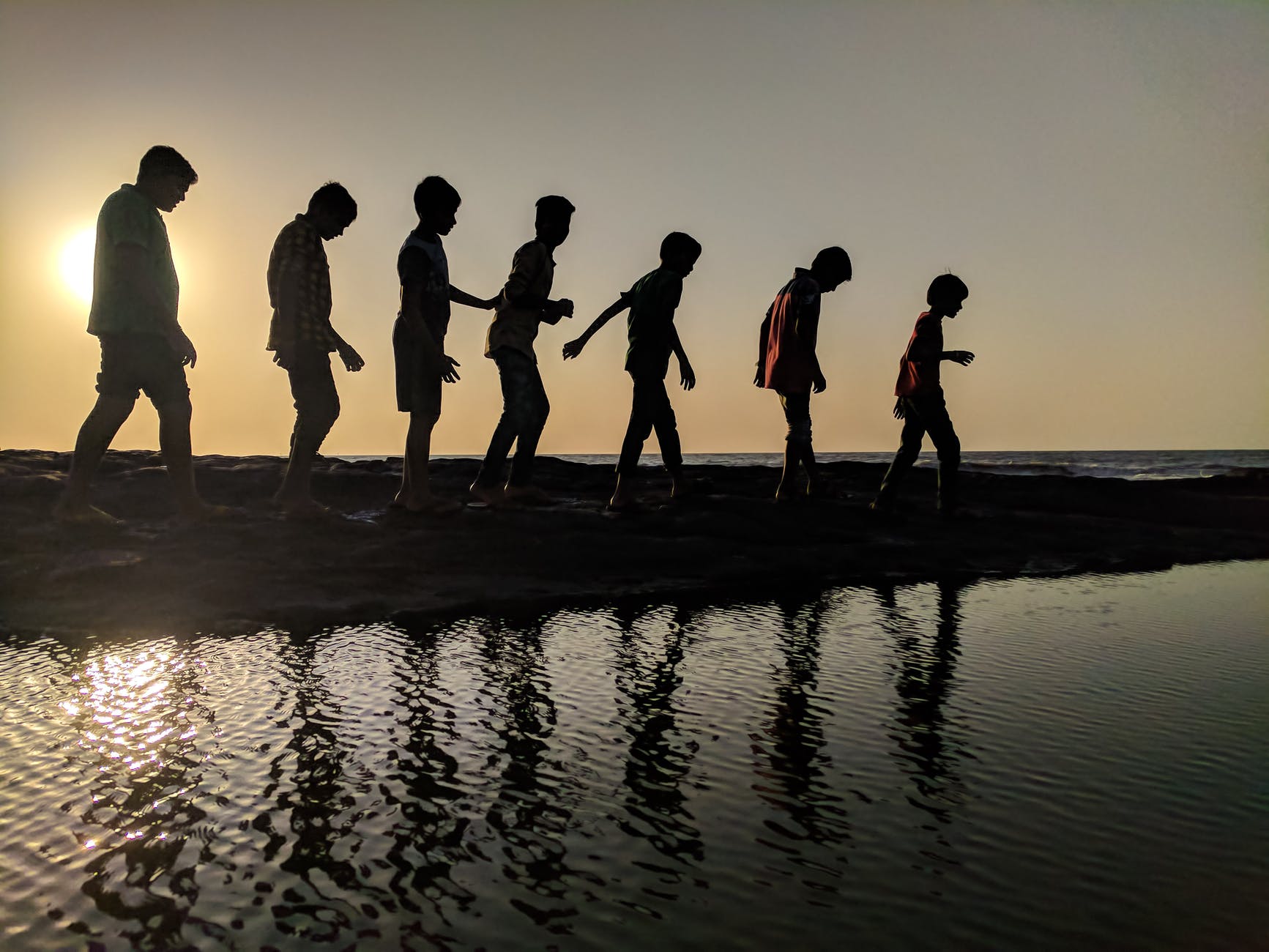 The silhouettes of a group of children walking near body of water. Are children our future?
