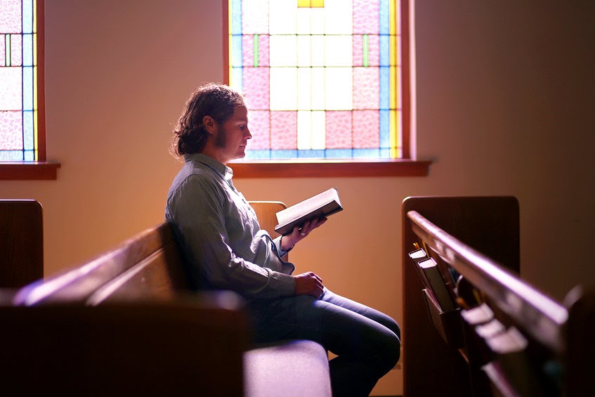 A person sitting in worship with a hymnal open.